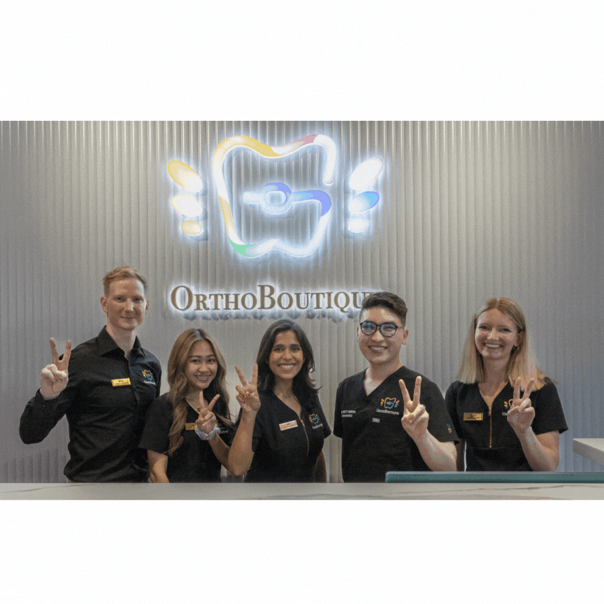 OrthoBoutique - happy staff showing their V sign for a group picture