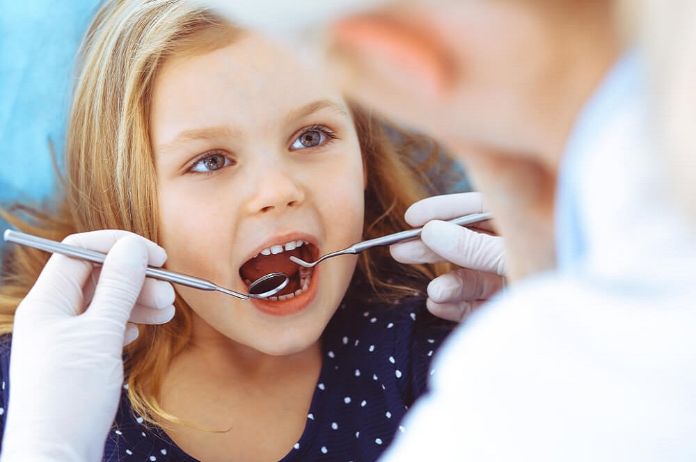 OrthoBoutique - a dentist checking a child teeth